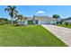 Charming single-story home featuring a lush lawn, brick driveway, and tropical landscaping with mature palm trees at 3725 Spyglass Hill Rd, Sarasota, FL 34238