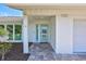 Charming front entrance showcasing updated stone flooring, updated blue door, white brickwork, and well-maintained landscaping at 3725 Spyglass Hill Rd, Sarasota, FL 34238