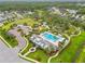 Aerial view showcasing a community clubhouse, pool, playground, and lush green spaces at 4021 Wildgrass Pl, Parrish, FL 34219