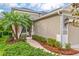Tan home featuring a side entrance with palm trees and lush landscaping at 4021 Wildgrass Pl, Parrish, FL 34219