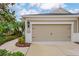 Attached one car garage of a well-maintained tan and white house with nicely manicured landscaping at 4021 Wildgrass Pl, Parrish, FL 34219