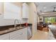 Kitchen featuring a stainless steel sink, white cabinets, granite countertops, and an adjacent living area at 4021 Wildgrass Pl, Parrish, FL 34219