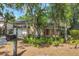 Inviting two-story home with a front porch and a two-car garage, surrounded by mature trees and lush landscaping at 4063 Woodview Dr, Sarasota, FL 34232