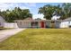 Charming single-story home featuring a well-manicured lawn, a vibrant red door, and mature trees at 4311 2Nd E Ave, Bradenton, FL 34208