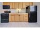 Functional kitchen featuring wooden cabinets, an electric stove and a black refrigerator at 441 Venetia Ave, North Port, FL 34287