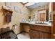 Traditional bathroom with a brown sink, toilet, wallpaper, vanity and a large mirror at 4711 Ocean Blvd, Sarasota, FL 34242