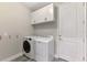 Well-organized laundry room featuring a front-load washer, dryer, and white cabinets at 4889 Antrim Dr, Sarasota, FL 34240