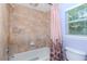 Bathroom featuring a tub and shower combination with tiled walls and window at 5151 Jasmine Way, Palm Harbor, FL 34685