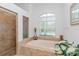 Bright bathroom featuring a soaking tub with a large window and tiled shower at 5151 Jasmine Way, Palm Harbor, FL 34685