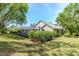 Beautifully landscaped backyard with view of the home's exterior, screened lanai, and outdoor entertaining area at 5151 Jasmine Way, Palm Harbor, FL 34685
