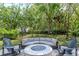 Outdoor living area with a round fire pit and comfortable seating with views of the trees at 5151 Jasmine Way, Palm Harbor, FL 34685