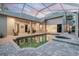 Covered pool area featuring brick pavers, a hot tub, and access to multiple rooms in the house at 5151 Jasmine Way, Palm Harbor, FL 34685