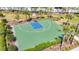 Aerial view of a basketball court with green and blue surface, surrounded by lush greenery and palm trees at 5688 Woodland Sage Dr, Sarasota, FL 34238
