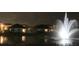 Nighttime view of neighborhood with community pond featuring illuminated fountain with nearby houses at 5688 Woodland Sage Dr, Sarasota, FL 34238