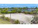 Sandy volleyball court with net surrounded by landscaping and greenery at 5688 Woodland Sage Dr, Sarasota, FL 34238