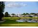 Picturesque golf course view with a water hazard, golfers, golf carts, and residential homes in the background at 6501 Stone River Rd # 209, Bradenton, FL 34203