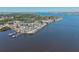 Waterfront community aerial view featuring waterfront homes, a pier, boat docks and the wide open bay beyond at 7 Braden Castle Dr, Bradenton, FL 34208