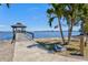 Charming waterfront pier with a covered gazebo and inviting pathway, near sandy shores and waving palm trees at 7 Braden Castle Dr, Bradenton, FL 34208