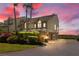 Coastal townhome features lush landscaping, brick paver driveway, and desirable under-house garage with sunset sky at 71 Tidy Island Blvd, Bradenton, FL 34210