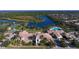 Stunning aerial view of the community clubhouse, pool, tennis courts, and scenic lake with fountain at 7664 Camminare Dr, Sarasota, FL 34238