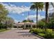 Community entrance with a covered structure, flag pole, beautiful landscaping, and brick-paved driveway at 7664 Camminare Dr, Sarasota, FL 34238