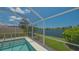 Screened-in pool with a picturesque view of the adjacent lake and lush landscaping at 7664 Camminare Dr, Sarasota, FL 34238