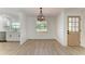 Bright dining room featuring modern light fixture, hardwood floors and adjacent kitchen at 826 Lillian Ln, Sarasota, FL 34243