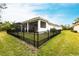 A well-manicured lawn surrounds a white one-story house with a black metal fence and screened patio at 1007 143Rd Ne St, Bradenton, FL 34212