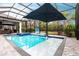 Screened-in pool and spa surrounded by lush landscaping and an umbrella at 1007 143Rd Ne St, Bradenton, FL 34212
