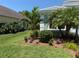 Landscaped front yard features mulch, flowers, palm trees, and green grass at 12272 Stuart Dr, Venice, FL 34293