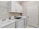 Functional laundry room with modern washer and dryer, sink, and ample storage cabinets for convenience at 12272 Stuart Dr, Venice, FL 34293