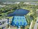 Aerial view of several pickleball courts, surrounded by a beautiful lake and lush landscaping within a vibrant community at 12272 Stuart Dr, Venice, FL 34293