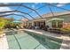 Stunning screened-in pool area with a spa, lush landscaping, and outdoor dining, perfect for entertaining at 12272 Stuart Dr, Venice, FL 34293
