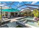 Luxurious pool and spa area with ample seating, an umbrella, and lush landscaping, perfect for relaxation and entertainment at 12272 Stuart Dr, Venice, FL 34293