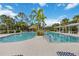 Community pool featuring tropical landscaping, lounge chairs, and striped cabanas at 12272 Stuart Dr, Venice, FL 34293