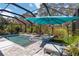Beautiful screened pool and spa area, complete with a sun umbrella and lounge chair, offering a relaxing outdoor space at 12272 Stuart Dr, Venice, FL 34293