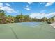 Well-maintained tennis court with green and blue surface, surrounded by lush greenery and a clear blue sky at 12272 Stuart Dr, Venice, FL 34293