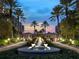 Spectacular exterior shot of a grand estate with a fountain, palm trees, and manicured landscaping at twilight at 1281 Gulf Of Mexico Dr # 704, Longboat Key, FL 34228