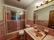 Retro bathroom with pink tile, bathtub with sliding glass door, and vintage fixtures at 2727 Waldemere St, Sarasota, FL 34239
