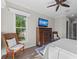 Comfortable bedroom featuring a ceiling fan and dresser with TV, complemented by views of the outdoors through the window at 275 Sapphire Lake Dr # 101, Bradenton, FL 34209