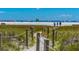 Sandy path with post and rope fence leading to a sunny beach with colorful umbrellas at 2839 Swifton Dr # 28, Sarasota, FL 34231