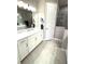Bright bathroom featuring double sinks, white cabinetry, gray tile floors, and a glass enclosed shower at 2918 Butterfly Jasmine Trl, Sarasota, FL 34240