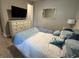 Cozy bedroom with light blue accent pillows, white dresser, and a large TV at 2918 Butterfly Jasmine Trl, Sarasota, FL 34240