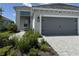 Charming home exterior showcasing a gray two-car garage, lush landscaping, and a paved driveway at 2918 Butterfly Jasmine Trl, Sarasota, FL 34240