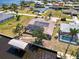 Aerial view showcasing waterfront home with boat lift, well-manicured lawn, and screened lanai at 3069 Stone St, Port Charlotte, FL 33981