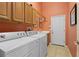 Laundry room with a side-by-side washer and dryer, storage cabinets, tile flooring, and an exterior door at 3752 Summerwind Cir, Bradenton, FL 34209