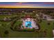 Beautiful aerial view of community pool and clubhouse area at sunset near landscaped grounds at 3814 Scrub Creek Run, Lakewood Ranch, FL 34211