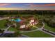 An aerial shot captures a clubhouse with a pool, landscaping, and nearby trees under a colorful sky at 3814 Scrub Creek Run, Lakewood Ranch, FL 34211