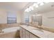 Elegant bathroom with dual sinks, granite countertops, a soaking tub, and a walk-in shower at 3814 Scrub Creek Run, Lakewood Ranch, FL 34211