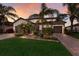 Beautiful one-story home featuring a three-car garage, manicured lawn, and lush landscaping at sunset at 3814 Scrub Creek Run, Lakewood Ranch, FL 34211
